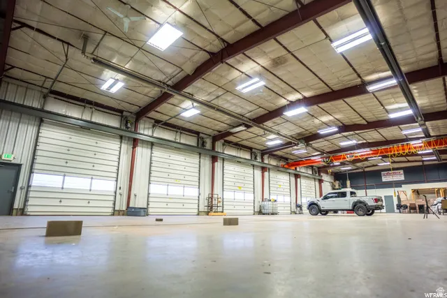 Spacious warehouse interior with multiple overhead doors, polished concrete flooring, overhead lighting, an exposed beam ceiling, and an integrated overhead crane system