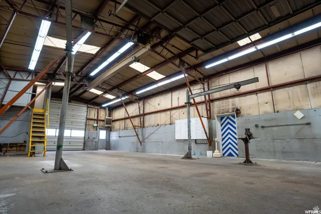 Expansive open-concept industrial space featuring a concrete floor, high ceilings with exposed metal trusses, multiple skylights, and fluorescent lighting
