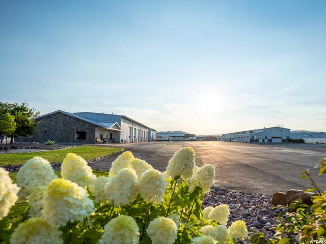 Expansive paved lot with multiple industrial-style buildings, featuring a stone-clad facade on one building and multiple bay doors