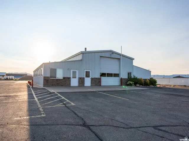 Metal-clad commercial building featuring a large roll-up door, multiple entry doors, and a stone-finish lower facade