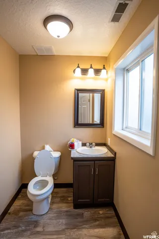 Bathroom with a single vanity, undermount sink, dark wood-finish cabinet, and wood-finish flooring