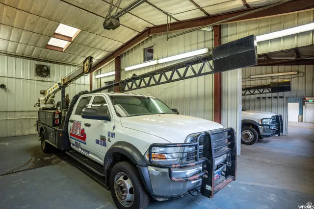 Concrete flooring, metal wall paneling, exposed structural beams, fluorescent lighting, and a skylight