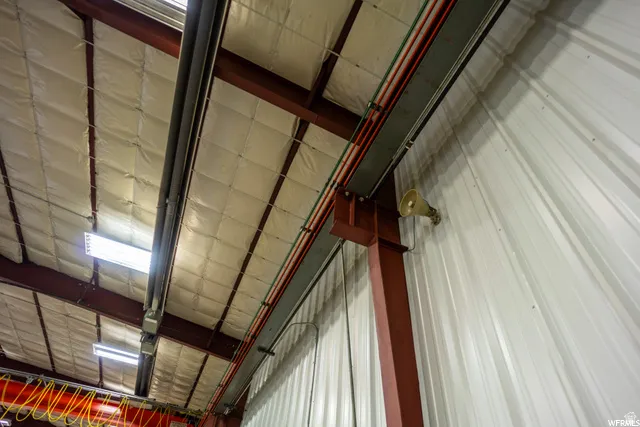 Insulated ceiling with exposed structural beams, fluorescent lighting fixtures, and corrugated metal wall paneling