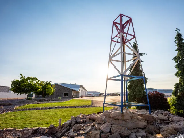 Landscaped grounds featuring a metal tower structure, stone accents, and mature evergreen trees