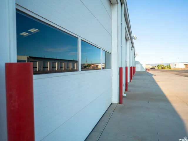 Corrugated metal exterior with window panels, concrete walkway, and red bollards