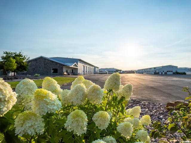 Expansive paved lot with multiple industrial buildings, stone façade accents, and metal roofs