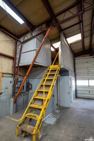 Industrial-style interior with exposed structural beams, a metal staircase, and a roll-up door