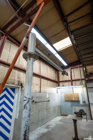 Exposed structural steel framing, high ceilings with skylight, fluorescent strip lighting, concrete flooring, and concrete block walls