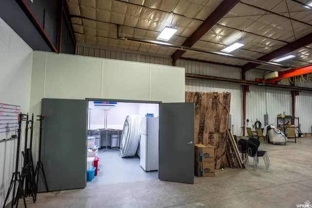 High ceilings with exposed metal trusses, concrete flooring, and an insulated ceiling