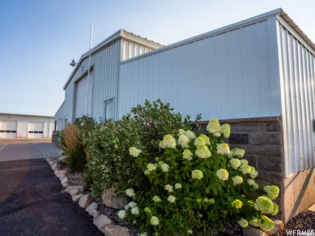 Metal siding exterior featuring a stone foundation and integrated landscaping