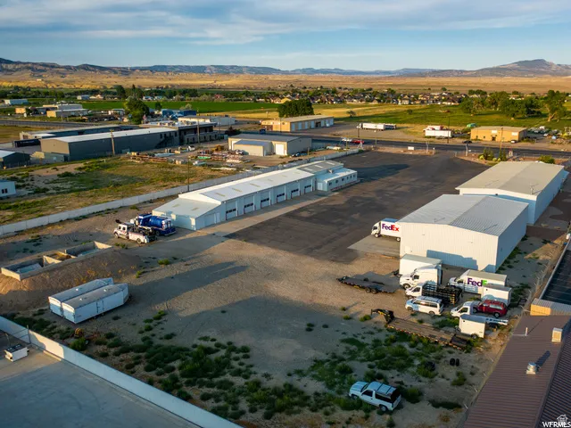 Expansive industrial property featuring multiple large warehouse structures, a paved parking area, and an open gravel lot