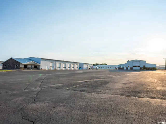 Paved lot with multiple metal-clad buildings, blue metal roofing, and numerous roll-up doors