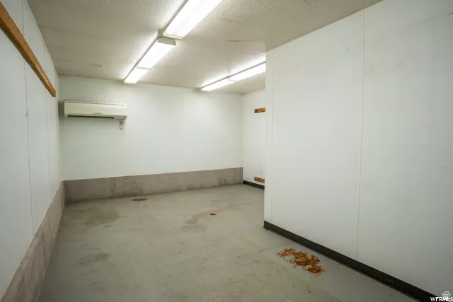 Concrete flooring with a white paneled wall system and fluorescent overhead lighting