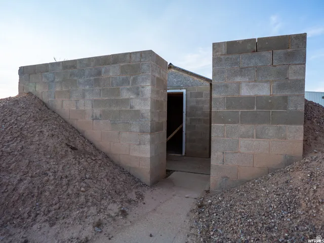 Cinder block structure featuring an open entrance and sloped earth embankments