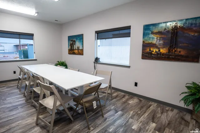 Wood-finish flooring, multiple windows with blinds, recessed lighting, and grey wall base trim