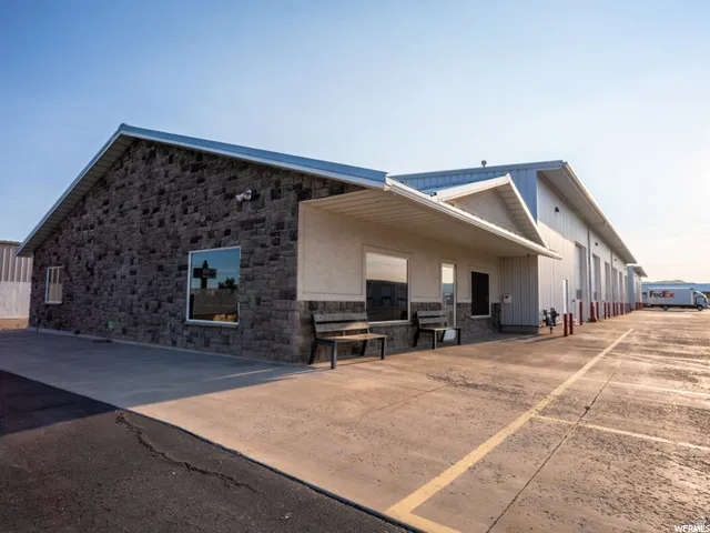 Stone and metal panel exterior, multiple roll-up garage doors, paved lot with marked spaces, covered entry, and security lighting