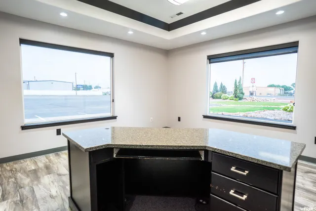 Modern office featuring expansive dual windows with dark-framed glass, abundant natural light, and panoramic vistas of surrounding grounds