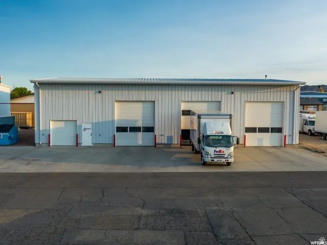 Metal-clad commercial building with multiple roll-up doors, a flat roof, and a paved concrete apron