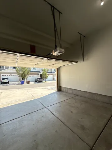 Attached garage with a concrete floor, automatic garage door opener, and painted walls