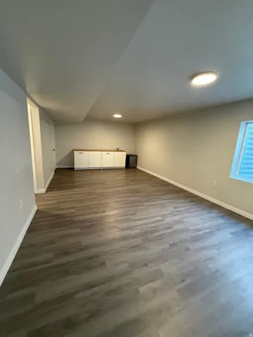 Spacious room featuring laminate wood-finish flooring, recessed lighting, and built-in cabinetry with a wood-finish countertop
