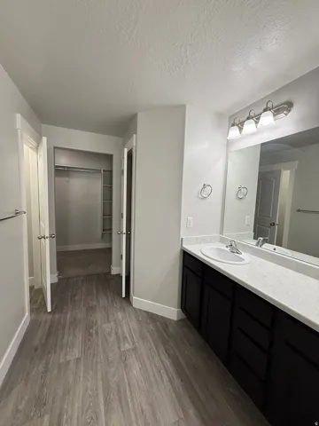 Vanity with a single basin sink, dark wood-finish cabinetry, and a white countertop
