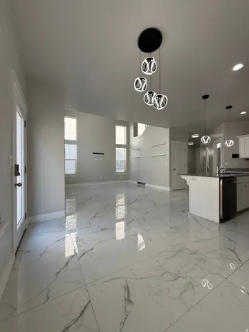 Open-concept interior featuring large-format tile flooring, multiple windows providing ample natural light, and contemporary pendant lighting fixtures
