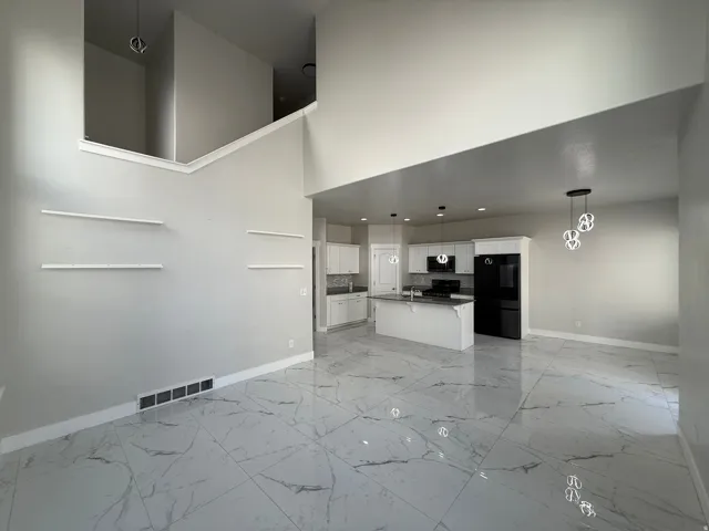 Open-concept living space with high ceilings and white marble-look flooring