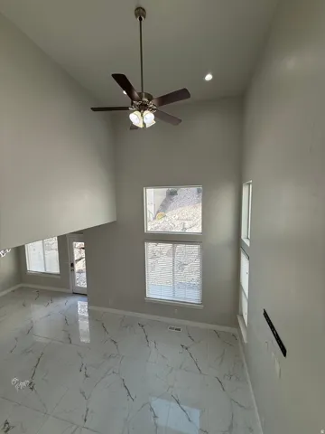 Soaring ceilings with recessed lighting, large format marble-look tile flooring, and multiple windows