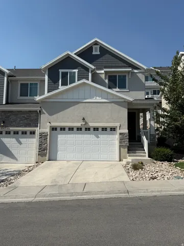 Stucco and stone facade with shake accent siding, attached two-car garage, and concrete driveway
