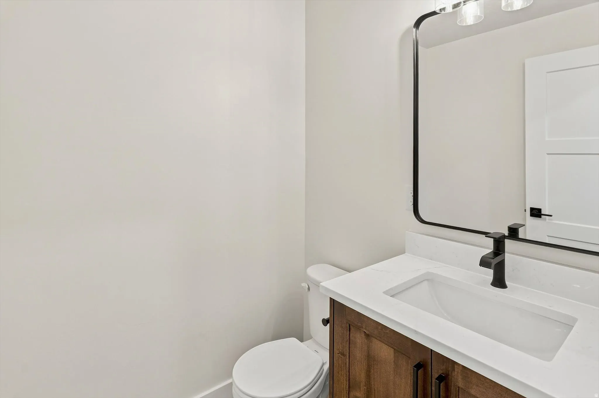Wood-finish vanity with an integrated rectangular sink, white countertop, and matte black faucet