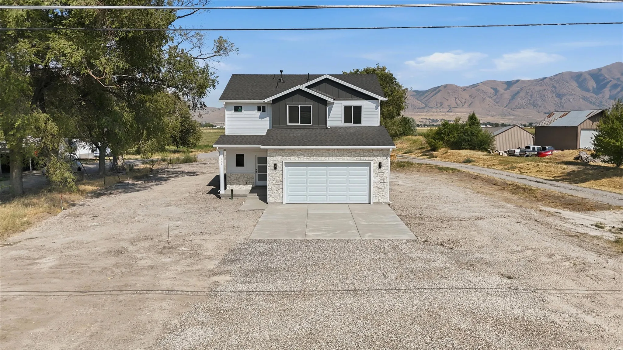 Two-story residence featuring light gray siding with dark gray accents and a white paneled garage door