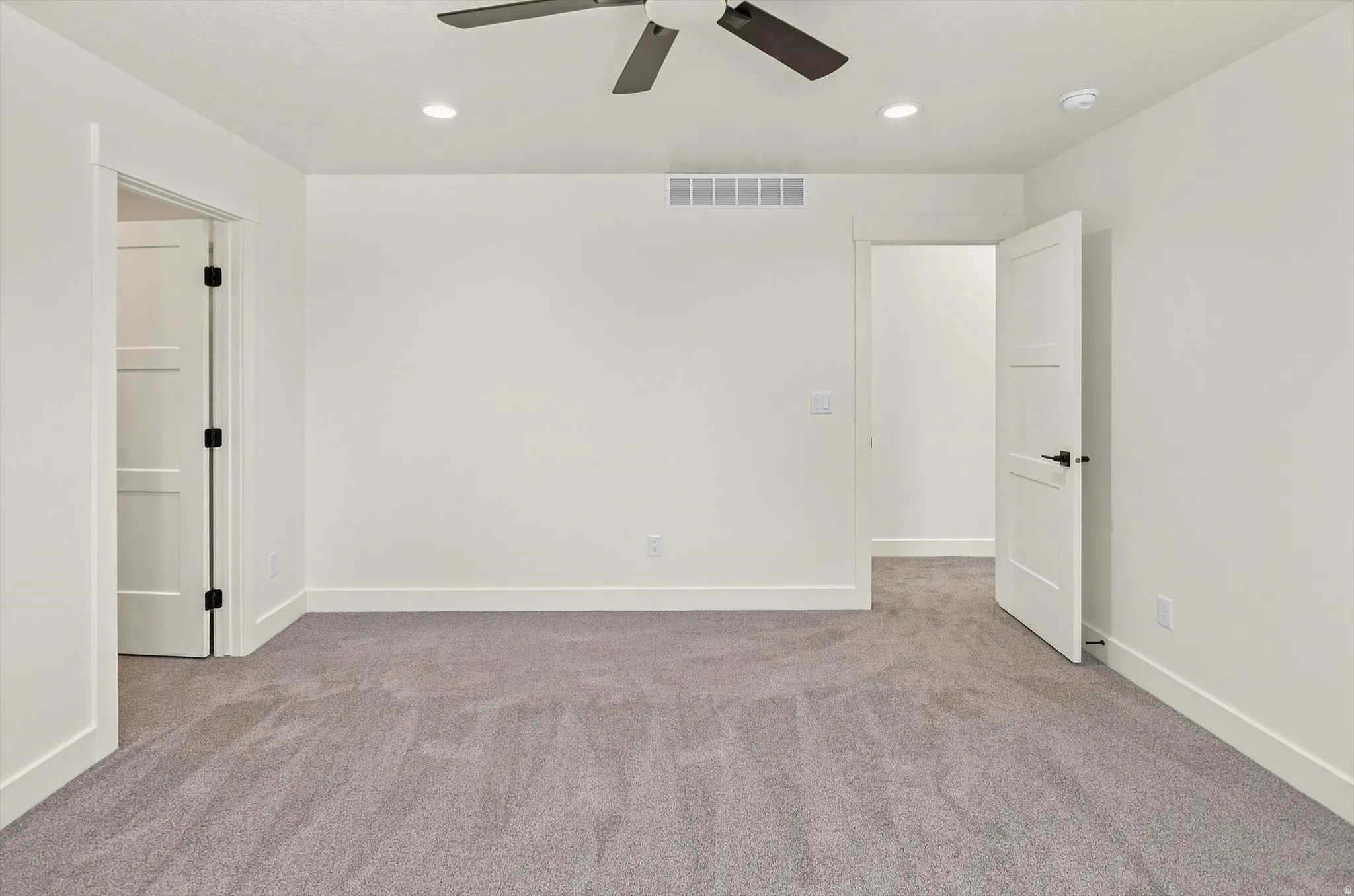 Recessed lighting, ceiling fan, neutral carpeting, and white interior doors with dark hardware