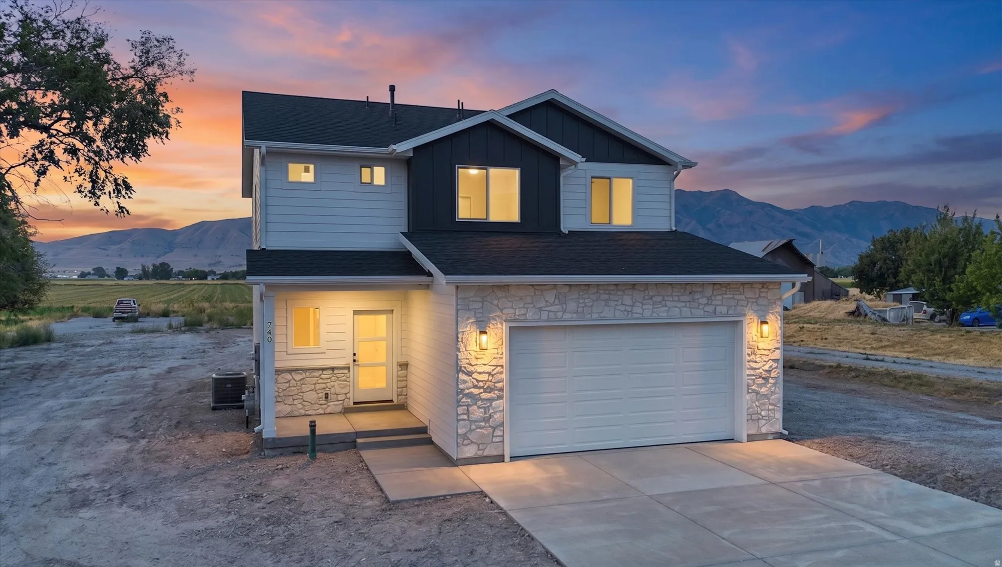 Two-story residence featuring a mixed-material exterior with light-colored stone accents and dark siding