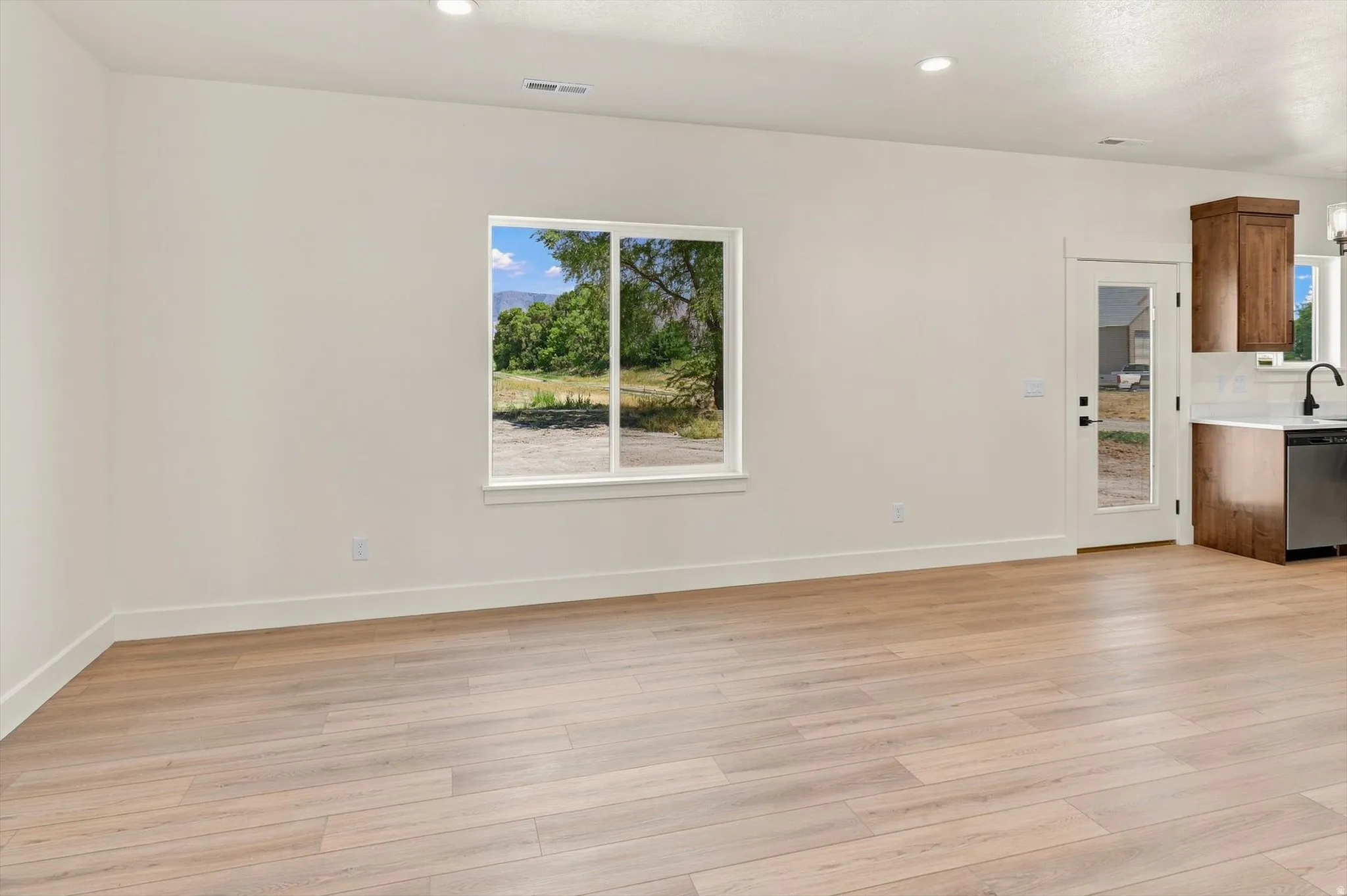 Wood-finish flooring, recessed lighting, white walls, and a glass-paneled door