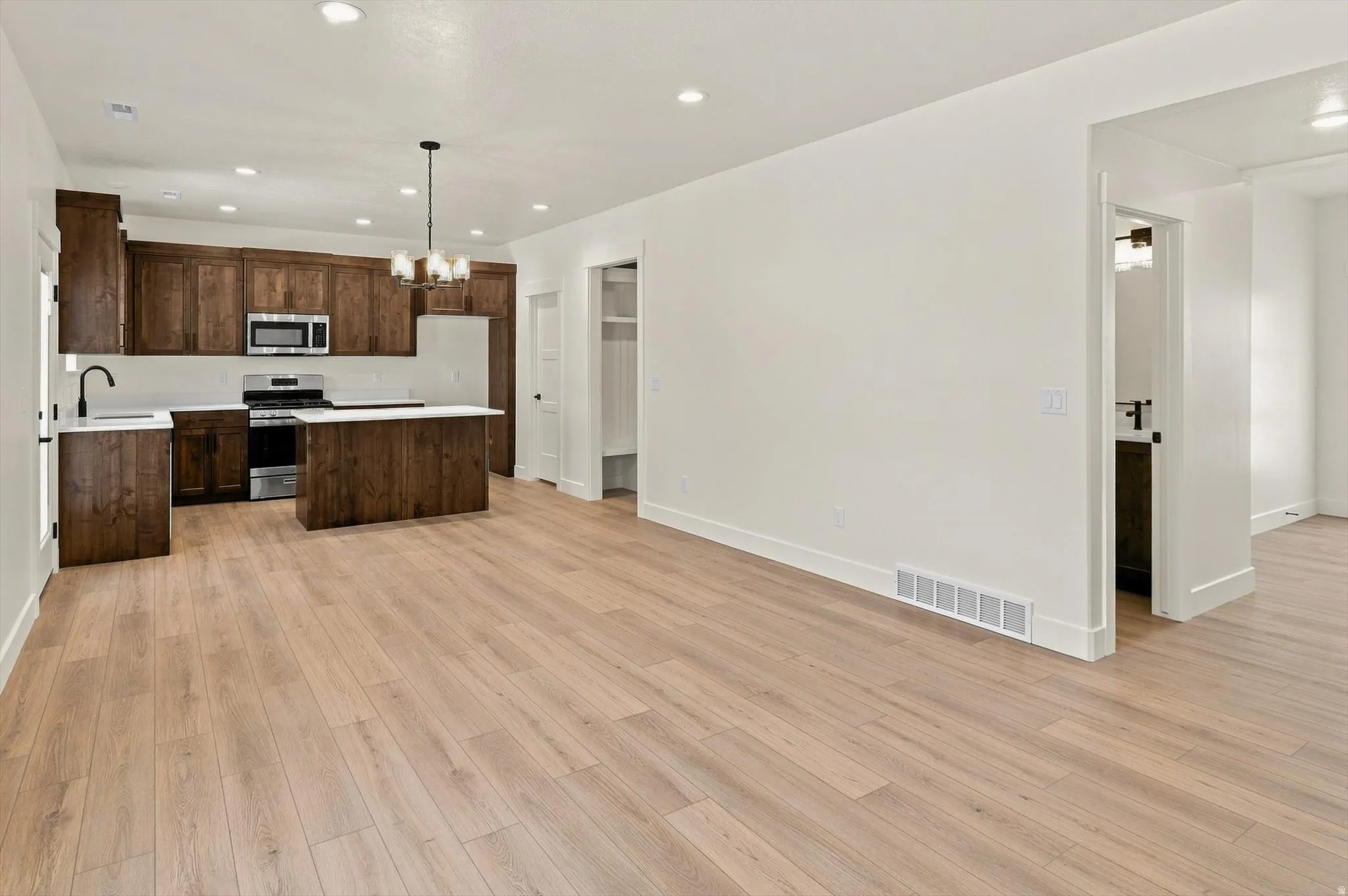 Spacious open-concept living area featuring wood-finish flooring, recessed lighting, and a modern kitchen