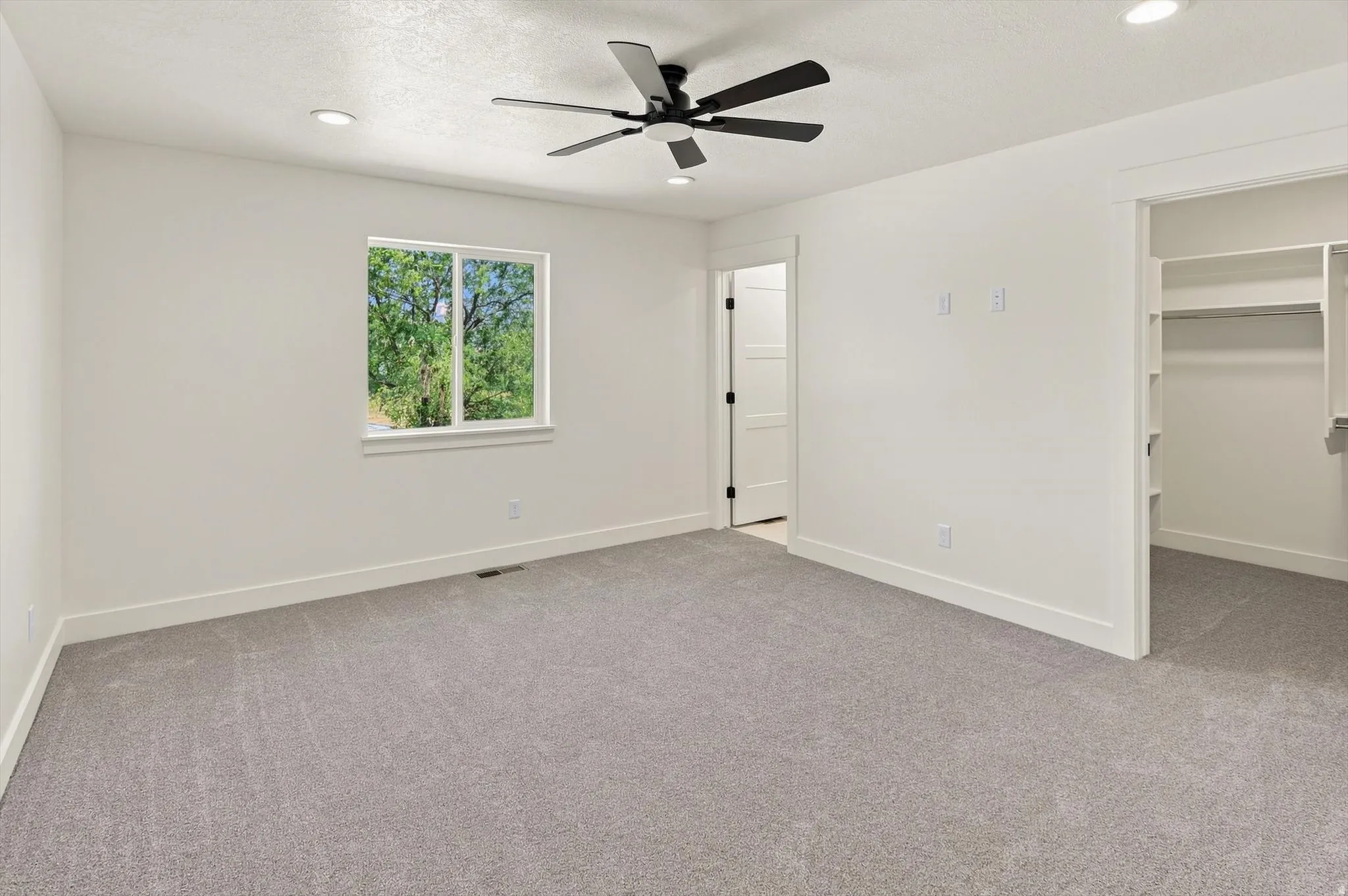 Spacious room featuring a ceiling fan, recessed lighting, a window, and soft gray carpeting
