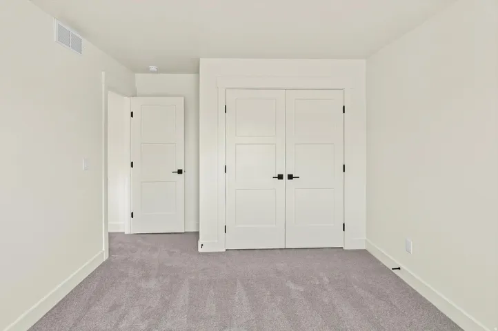 Neutral-toned carpeting, white walls, white trim, and white doors with matte black hardware