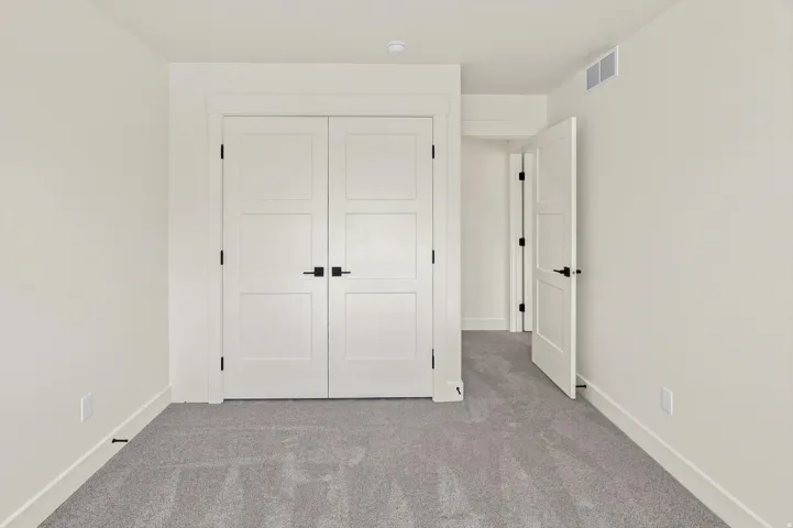 White paneled doors with matte black hardware, light gray carpeting, and white wall finishes
