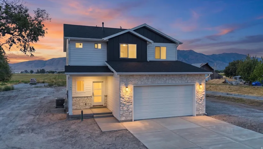 Two-story residence featuring a mixed-material exterior with light-colored stone accents and dark siding