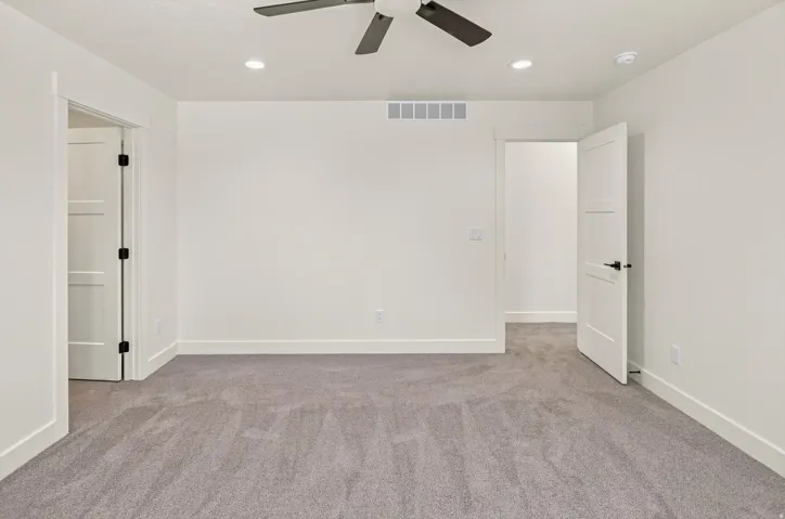 Recessed lighting, ceiling fan, neutral carpeting, and white interior doors with dark hardware