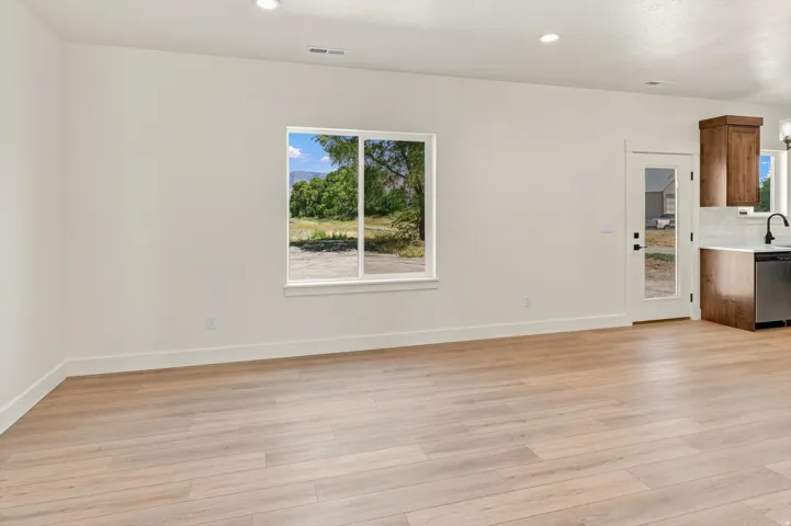 Wood-finish flooring, recessed lighting, white walls, and a glass-paneled door