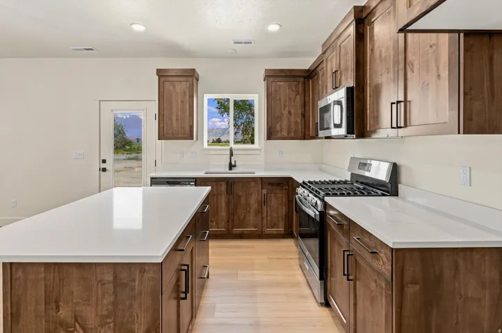 Kitchen featuring wood-finish cabinetry, white countertops, a large center island, and stainless steel appliances