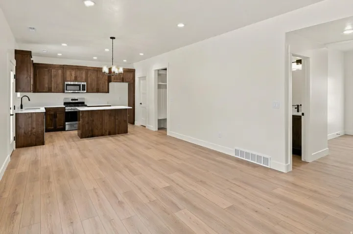 Spacious open-concept living area featuring wood-finish flooring, recessed lighting, and a modern kitchen