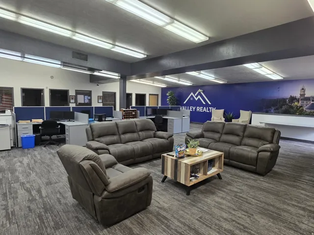 Open-concept commercial interior featuring patterned carpet and ceiling-mounted fluorescent lighting