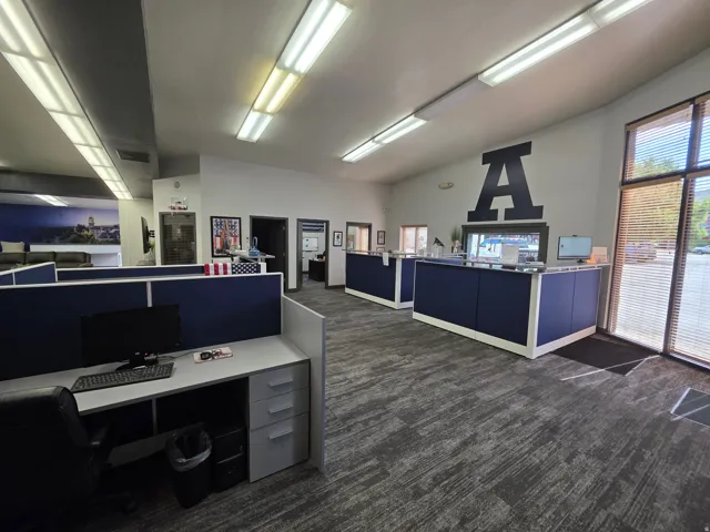 Open-plan office space featuring modular workstations, reception counters, and patterned carpet flooring