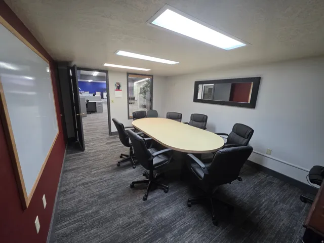 Conference room with textured carpeting, recessed fluorescent lighting, and a whiteboard