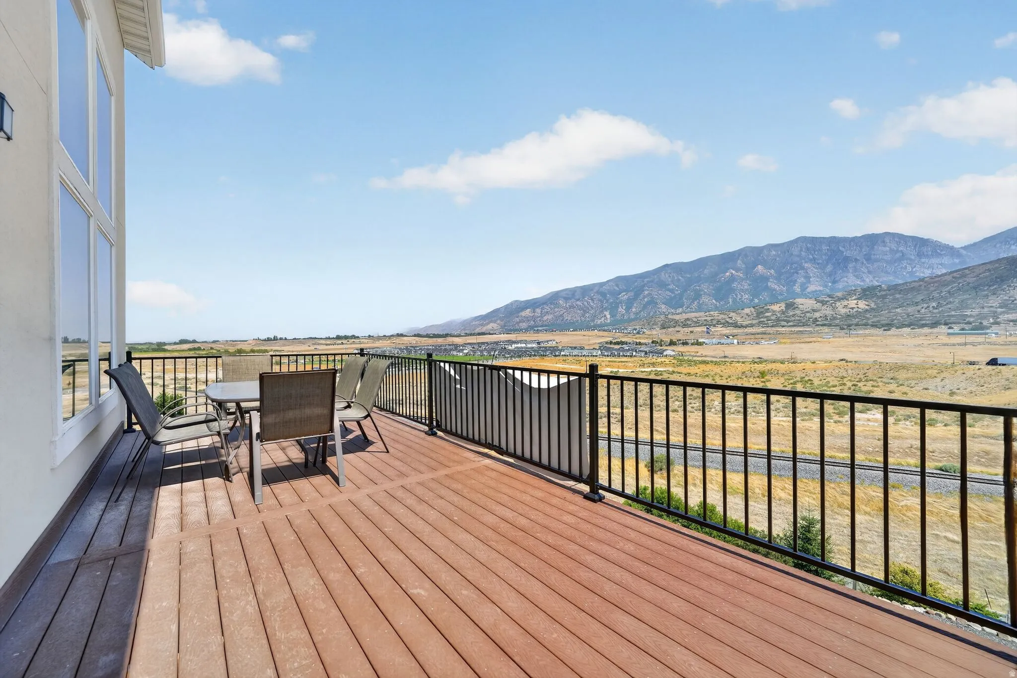 Expansive outdoor deck featuring wood-look flooring, a black metal railing, and large windows