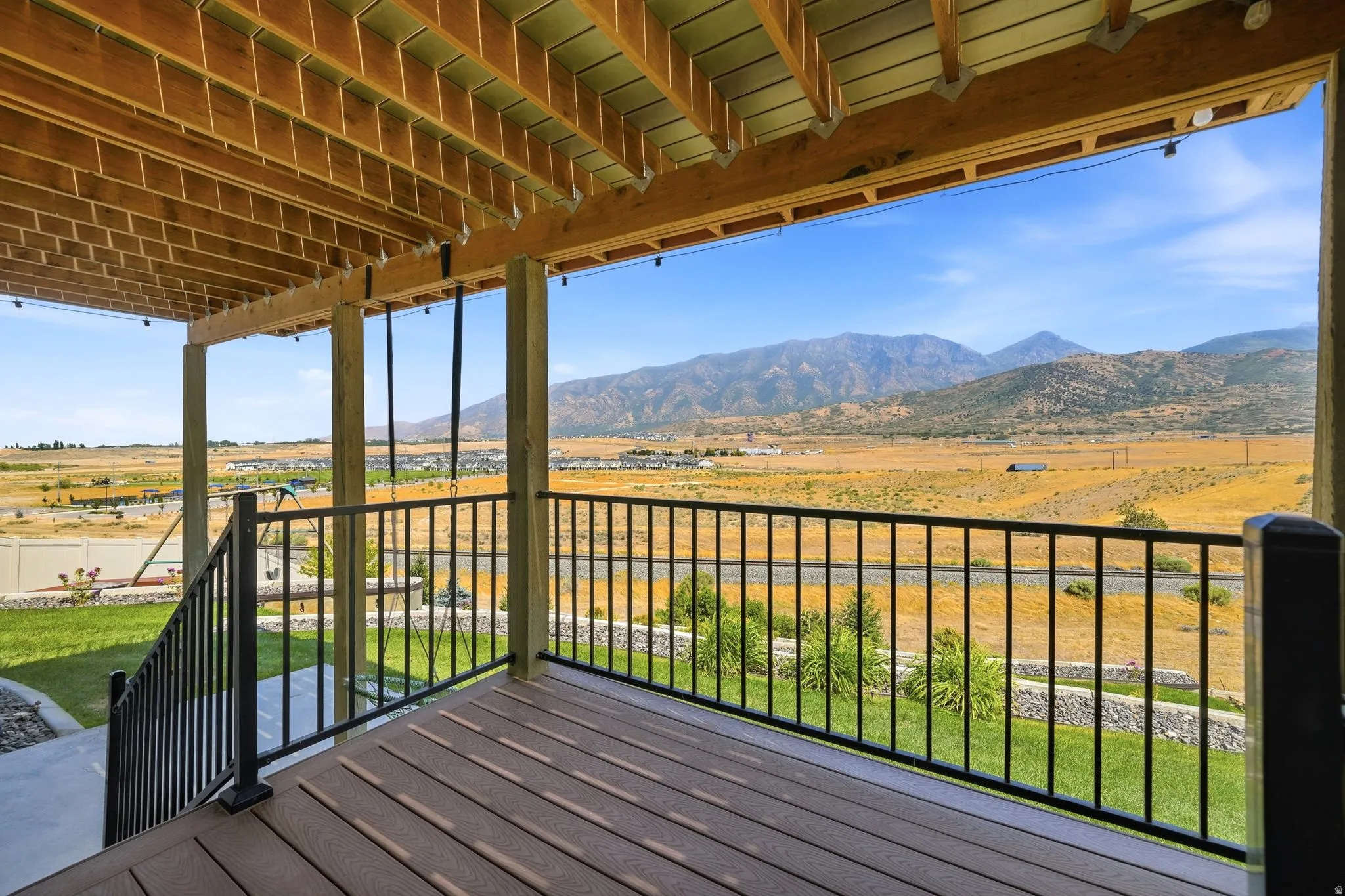 Expansive outdoor deck with composite decking and black metal railings, supported by substantial wood beams