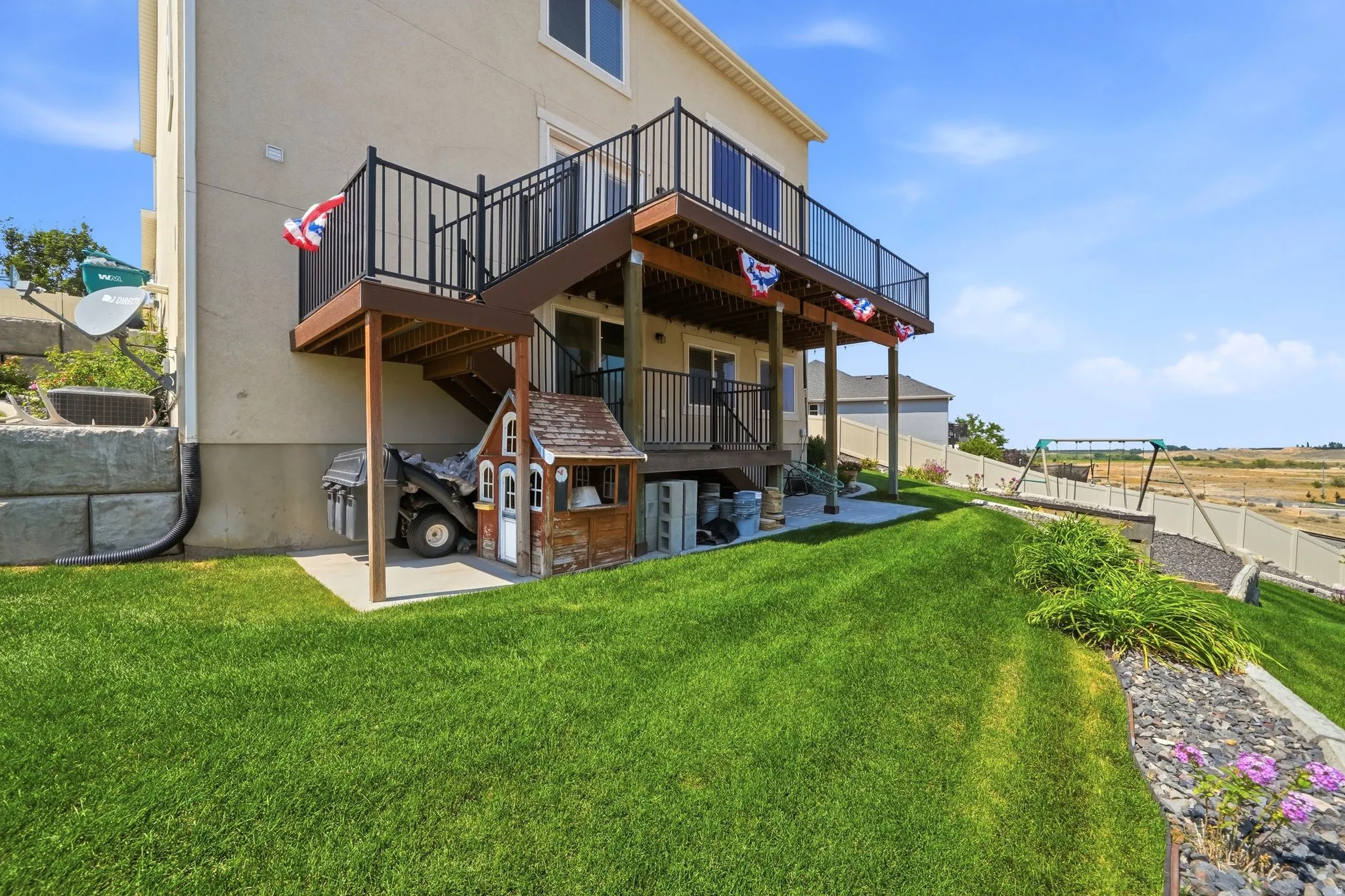 Two-story exterior with a ground-level patio and a raised deck with dark railings