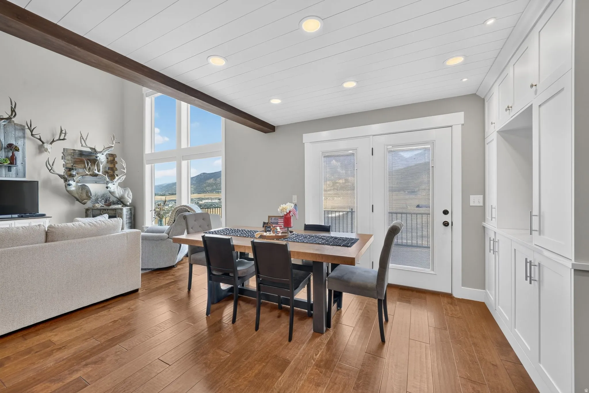 Hardwood flooring, white shiplap ceiling with recessed lighting, exposed ceiling beam, built-in cabinetry, and double glass doors